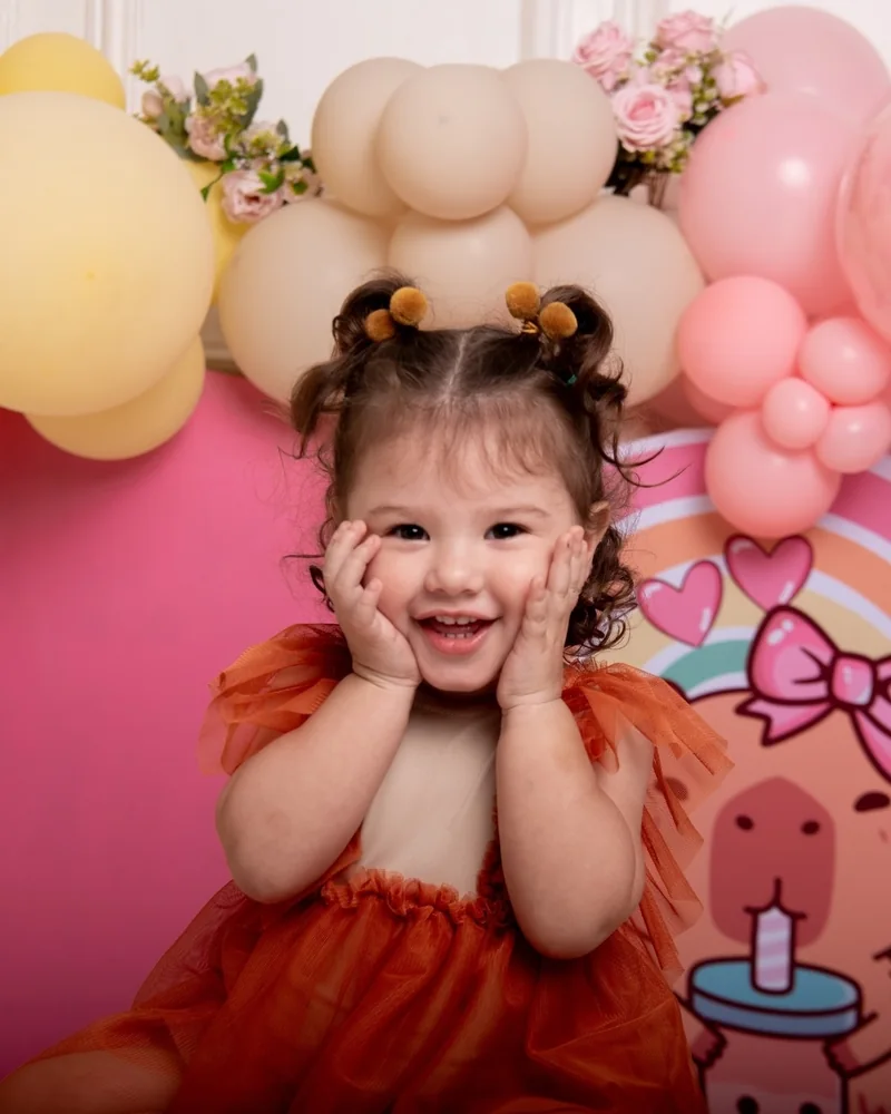 Niña con vestido naranja y las manos en la cara en su sesión pre cumple